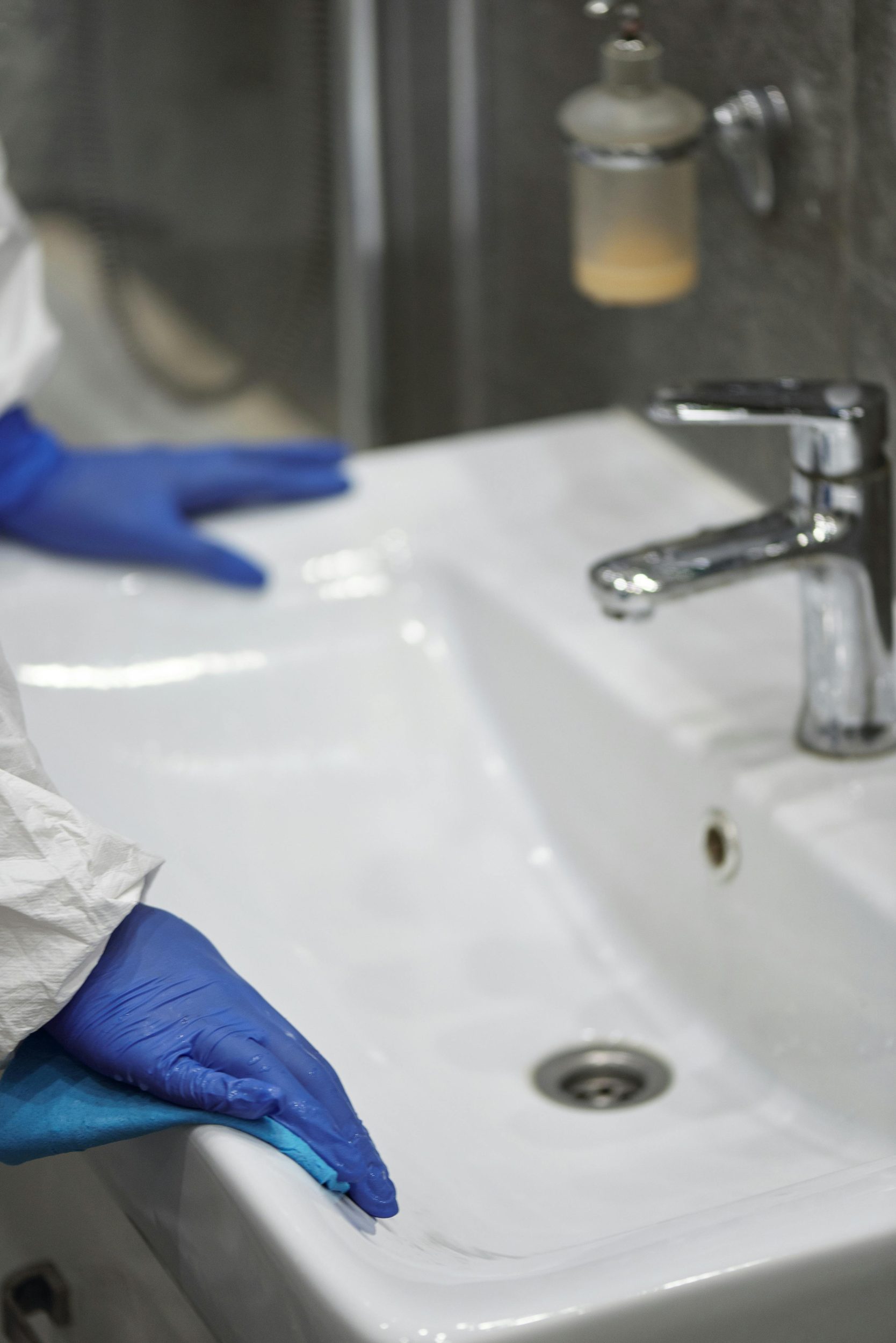 Person wearing gloves inspecting a household sink.